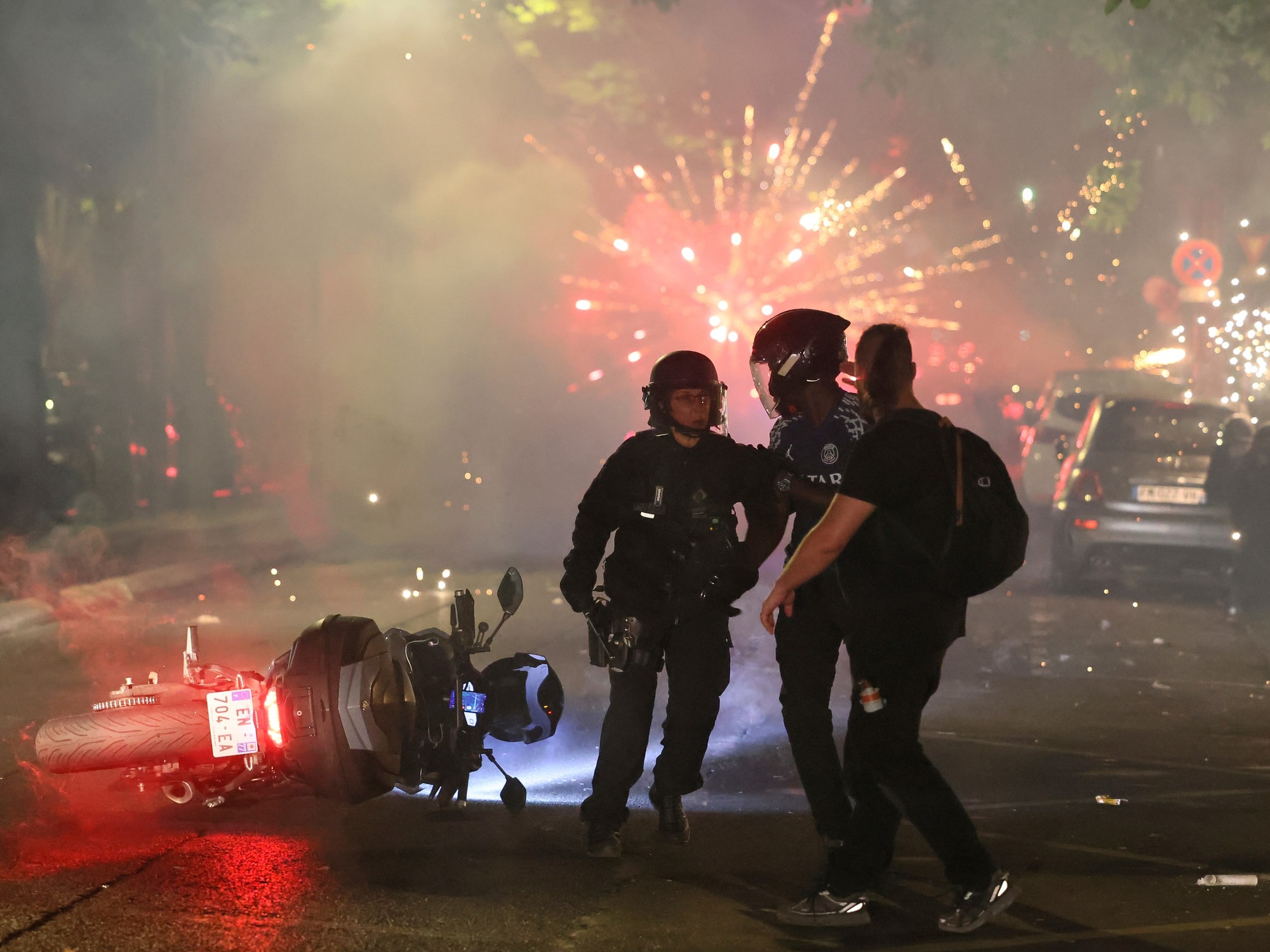 Imagen de la policía francesa intentando controlar una multitud de hinchas del Paris Saint-Germain en las calles de París durante los festejos de la Champions League.