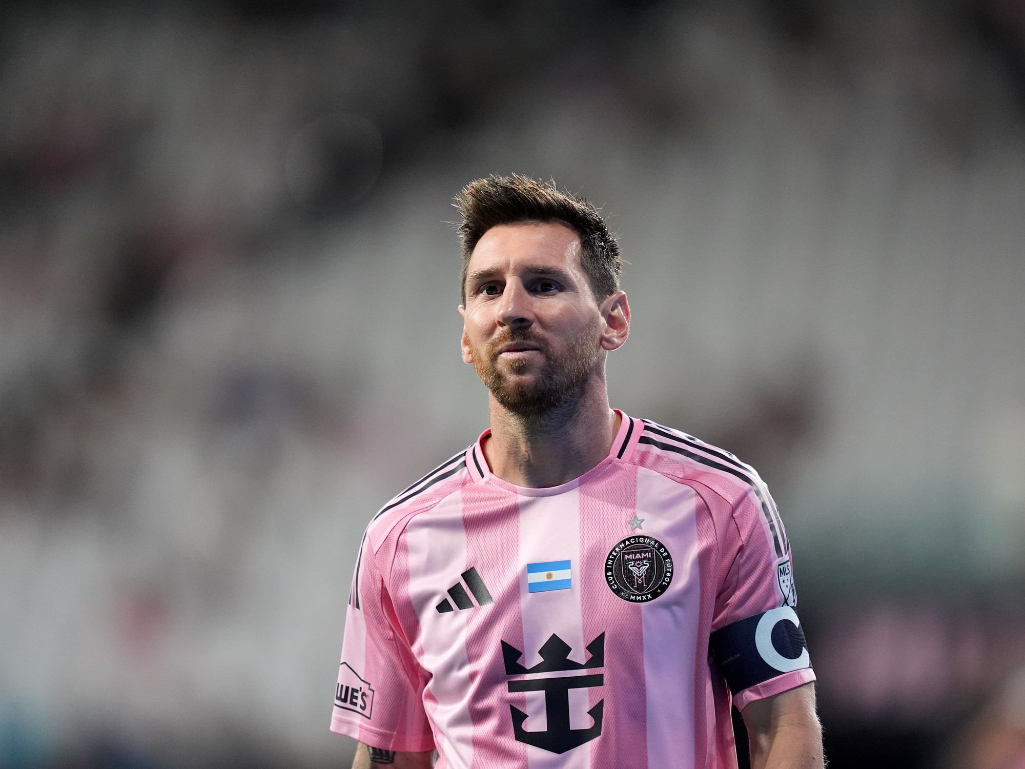 Lionel Messi caminando fuera del campo de juego con una expresión de molestia durante un partido de Inter Miami.