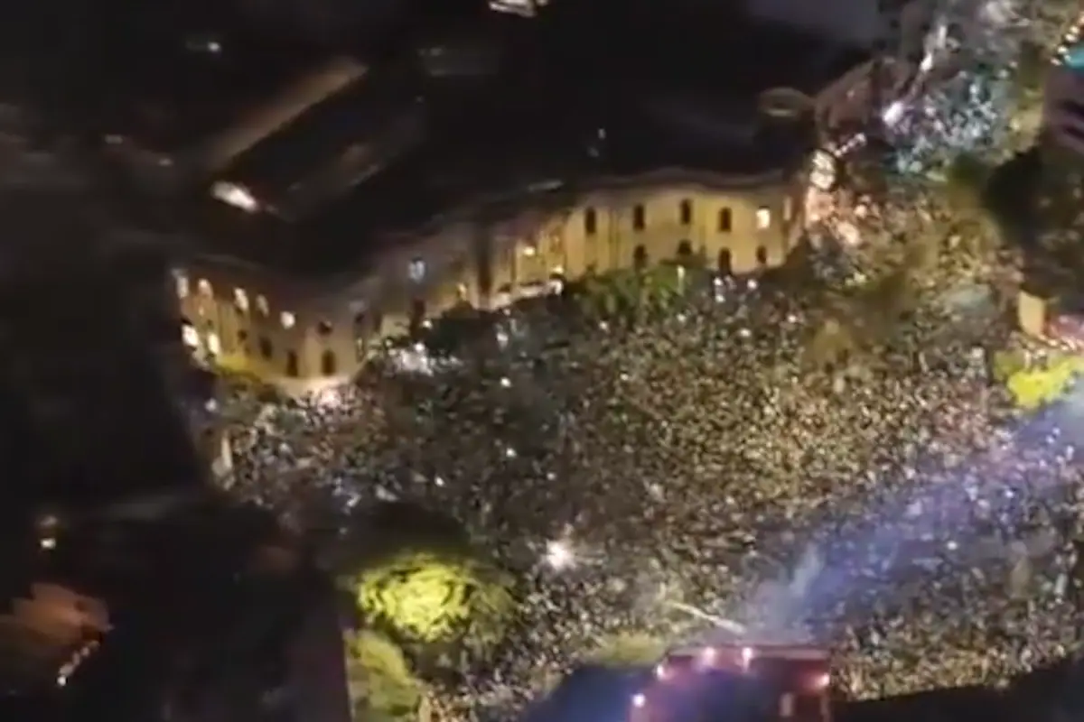 Multitud de hinchas de Belgrano celebrando en las calles de Córdoba con banderas y fuegos artificiales tras ganar el campeonato.