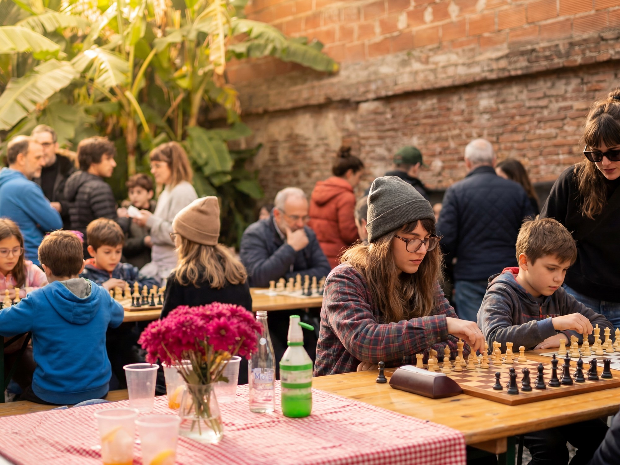 Personas jugando al ajedrez en un galpón ambientado, con mesas dispuestas y música en vivo de fondo.