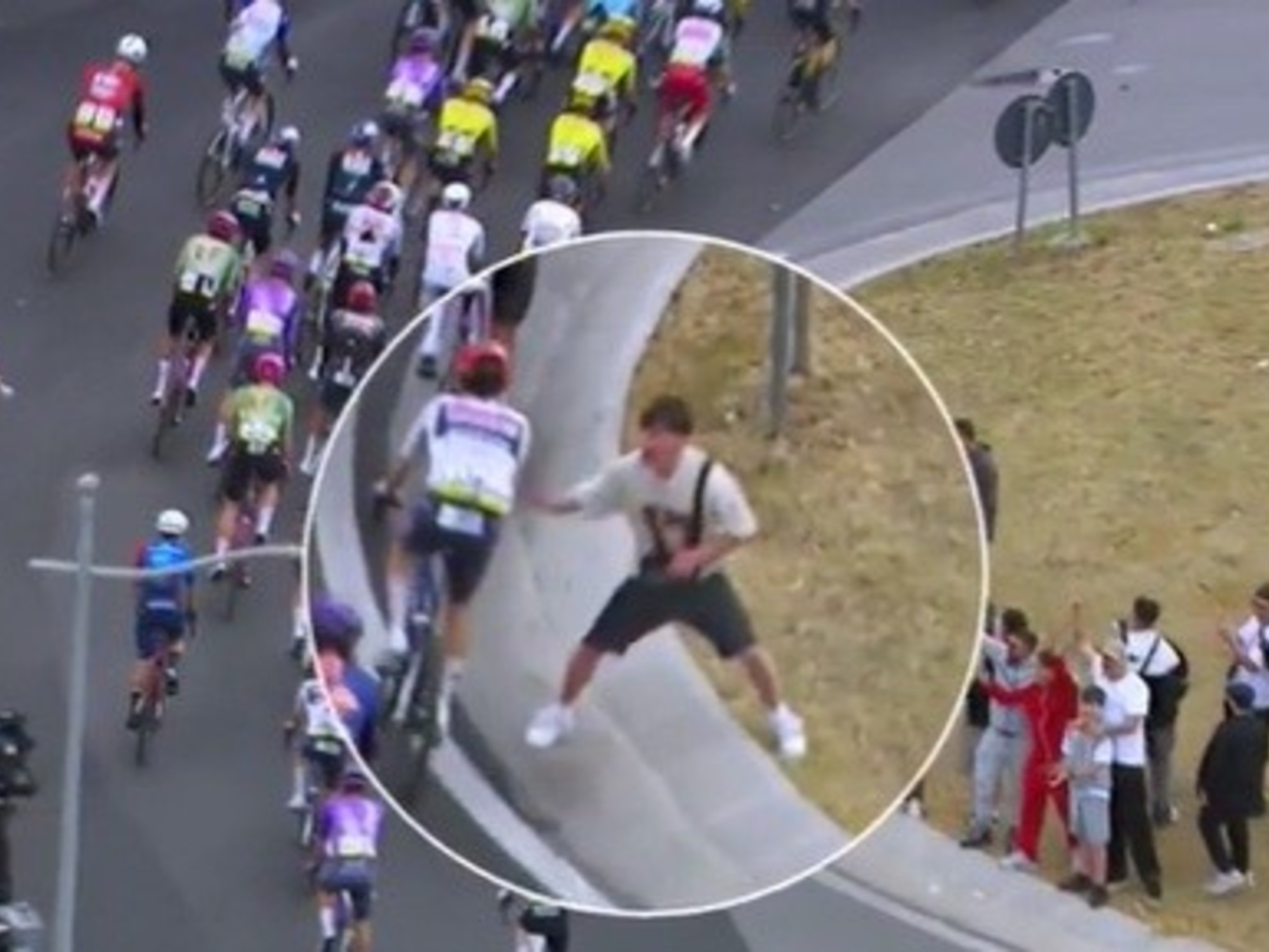 Un pelotón de ciclistas compitiendo en el Giro de Italia, con espectadores a los costados del camino.