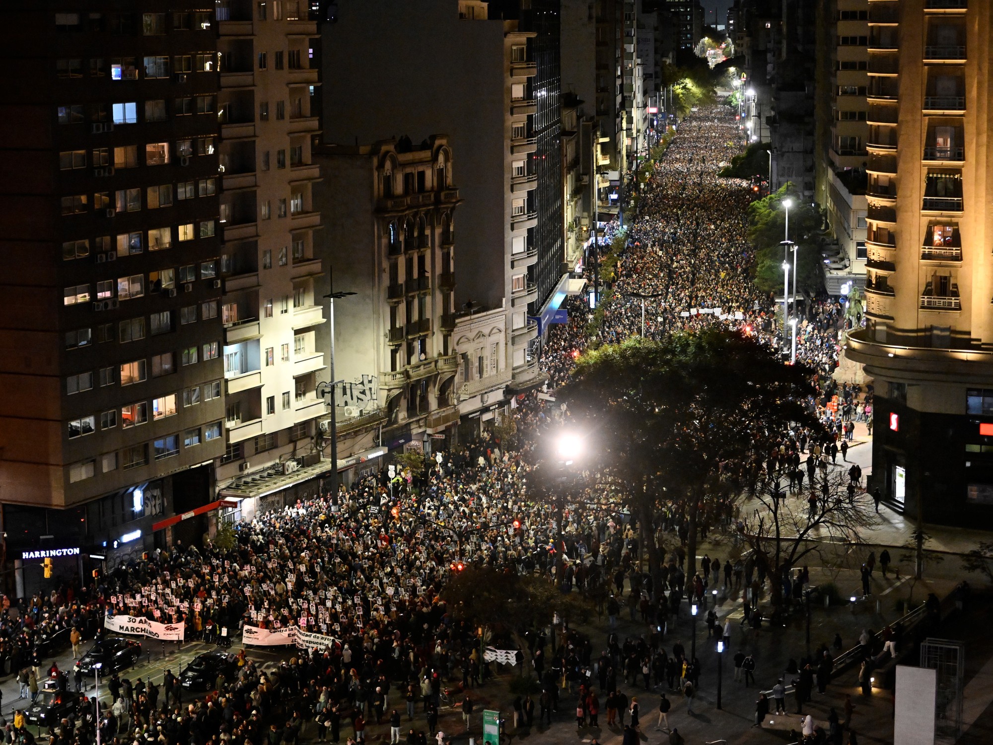 Multitud marchando en silencio por una avenida de Montevideo, portando carteles con fotos de personas desaparecidas.