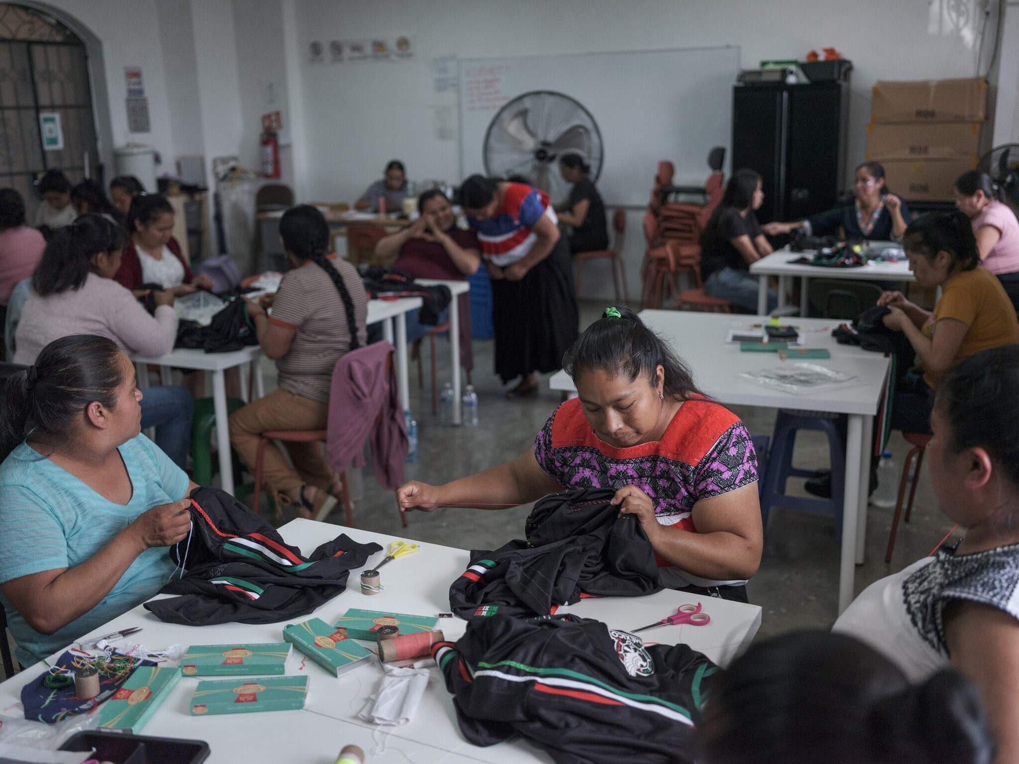 Mujeres indígenas nahuas trabajando en la confección de camisetas bordadas a mano para el Mundial de Fútbol en Naupan, México.