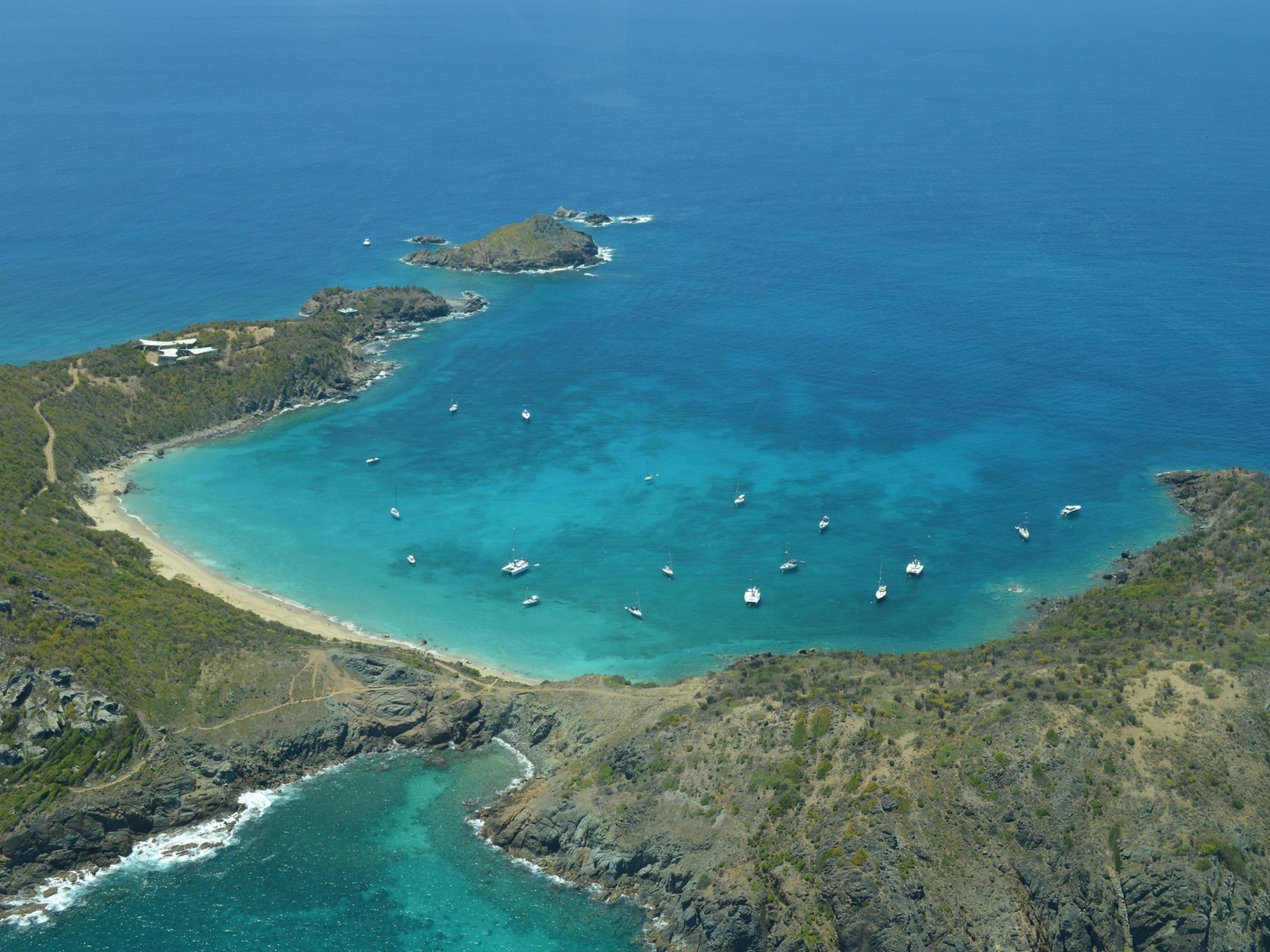Vista aérea de la isla Saint Martin/Sint Maarten, mostrando la división territorial entre la parte francesa y la parte neerlandesa, con aguas turquesas y vegetación exuberante.