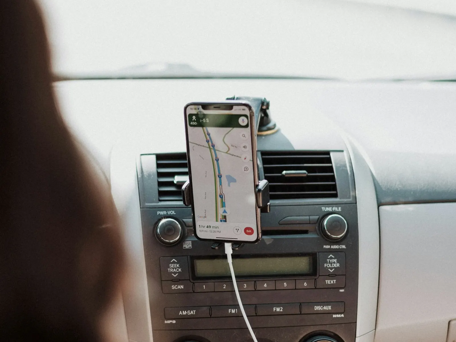 Imagen de un auto en movimiento, con un conductor distraído mirando su celular mientras carga.