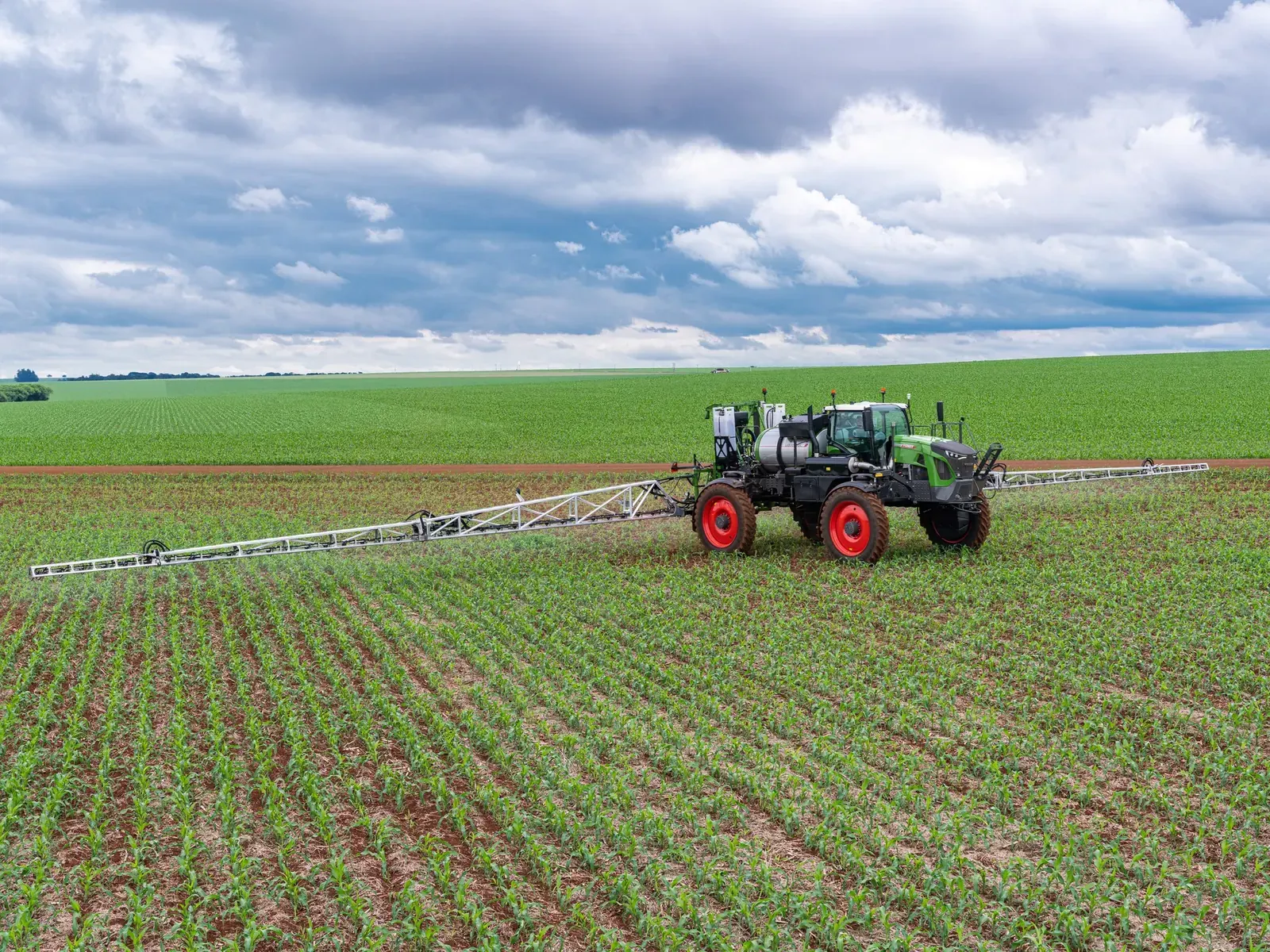 Productor agropecuario en un campo argentino supervisando la aplicación de fitosanitarios, con maquinaria agrícola de fondo.