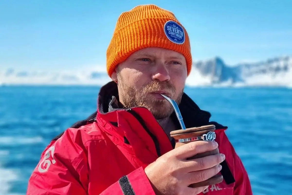 Un hombre sonriente de origen europeo, Maxim, posa en un paisaje argentino, con el objetivo de ilustrar su historia de viaje y búsqueda de refugio.