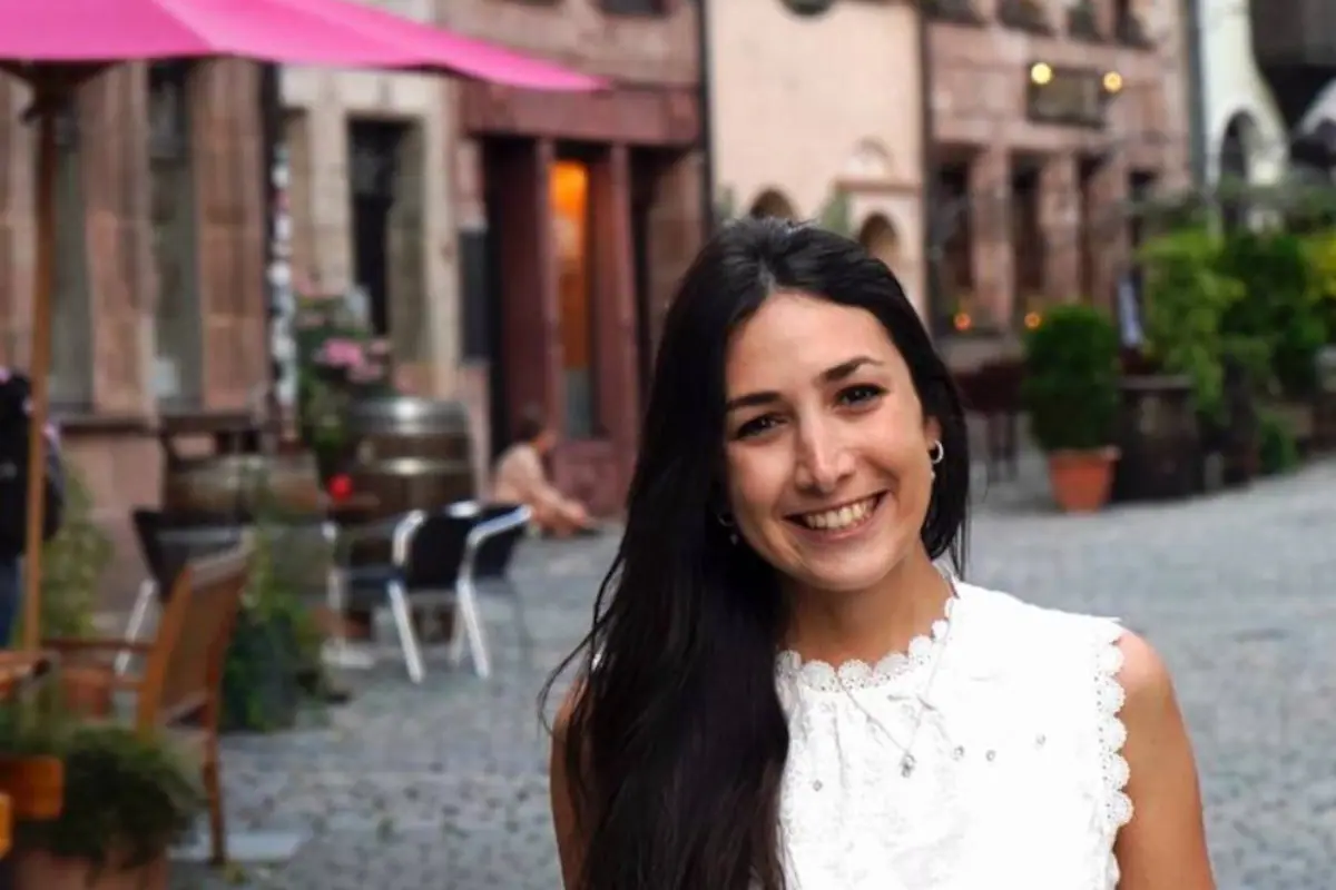 Carolina Biagiotti, una joven argentina, sonriendo mientras camina por una calle histórica de Núremberg, Alemania.