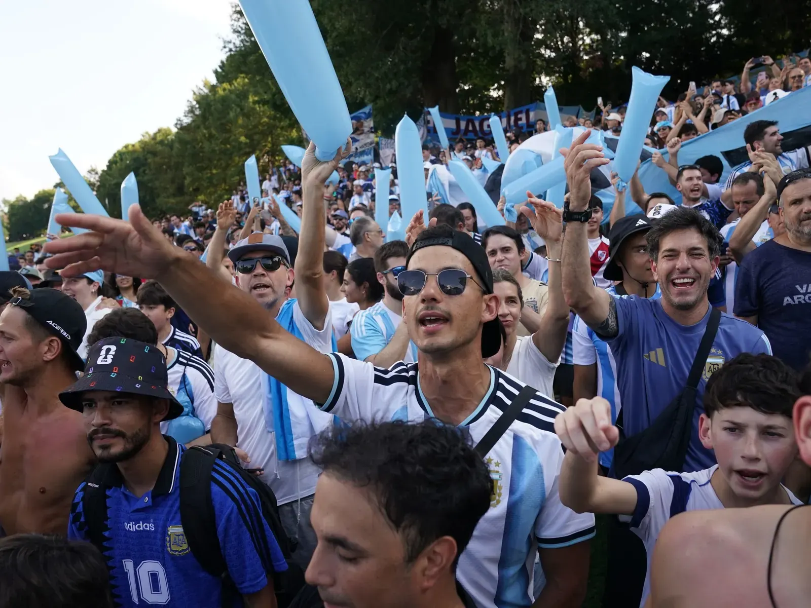 Hinchas argentinos saltando y cantando en apoyo a su selección nacional en un partido de fútbol.