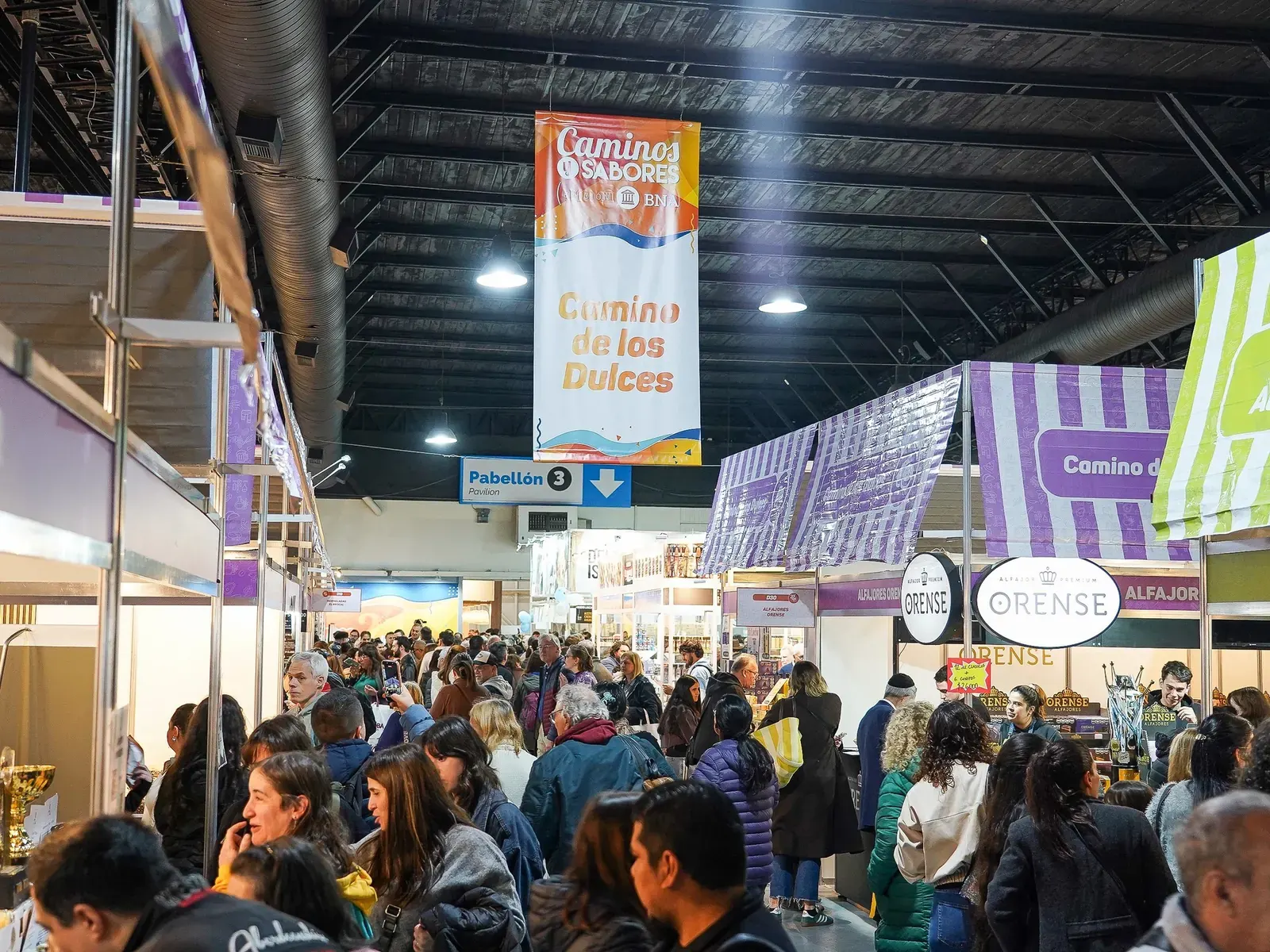 Vista general de la feria Caminos y Sabores con stands de diferentes provincias y público recorriendo los pasillos.
